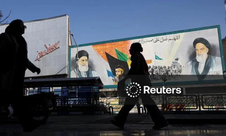 People walk near a mural featuring images of Iran's Supreme Leader Ayatollah Ali Khamenei and leader of Iran's 1979 Islamic Revolution Ayatollah Ruhollah Khomeini, in Tehran