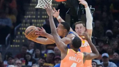 Orlando Magic guard Desmond Bane, left, goes to the basket between Cleveland Cavaliers center Evan Mobley (4) and guard Sam Merrill, right, in the first half of Tuesday's game in Cleveland.
