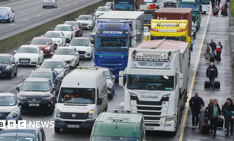 Irish fuel protests: People walk with luggage past heavy traffic on Dublin's M50